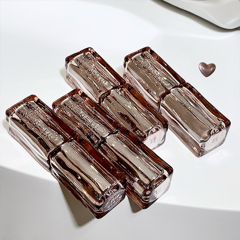 Set of four transparent brown lipstick containers on a white surface
