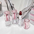 Set of lipsticks with clear casings and red lipstick on a white surface.