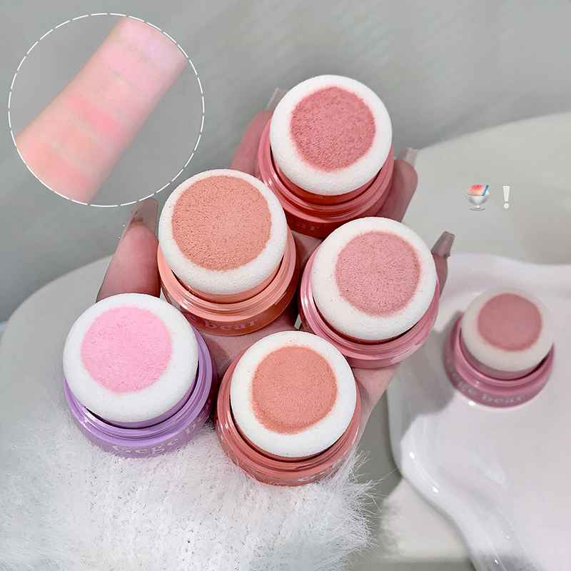 Set of pink and purple makeup blush products with applicators on a white surface.