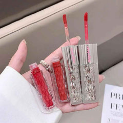 Hand holding a set of red lip glosses with a clear case.