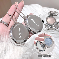 Silver gege bear blush with 'Gege bear' branding held by a hand, with a blurred background.