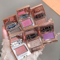 six different colors of eyeshadow palette on a hand of a lady against a grey backgroud 