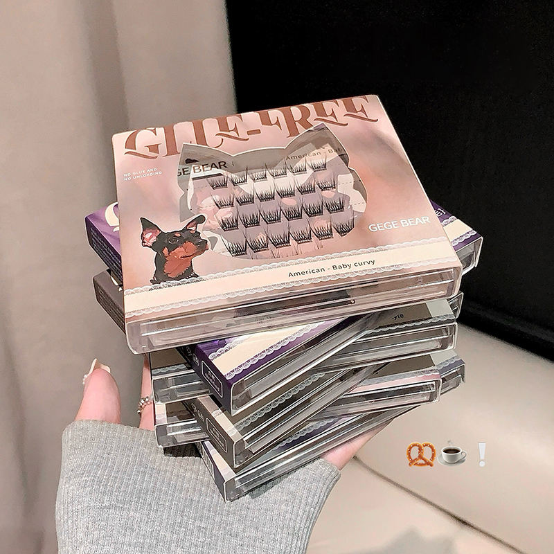 Stack of false eyelash boxes held by a person, with a neutral background
