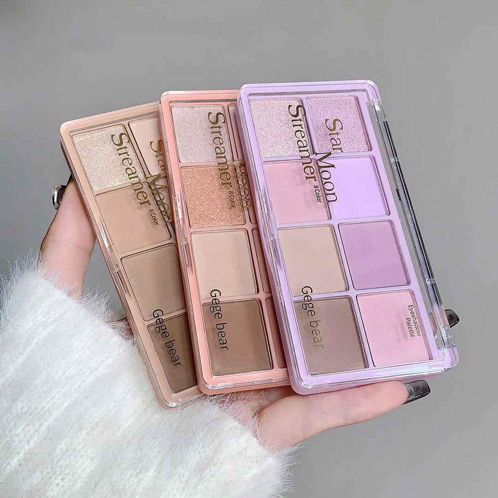 Three Eye-shadow palette with different color schemes held by a person wearing a white fur coat.