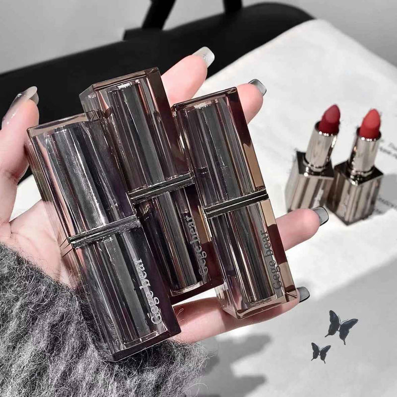 Close-up of three lipsticks held by a hand with a blurred background