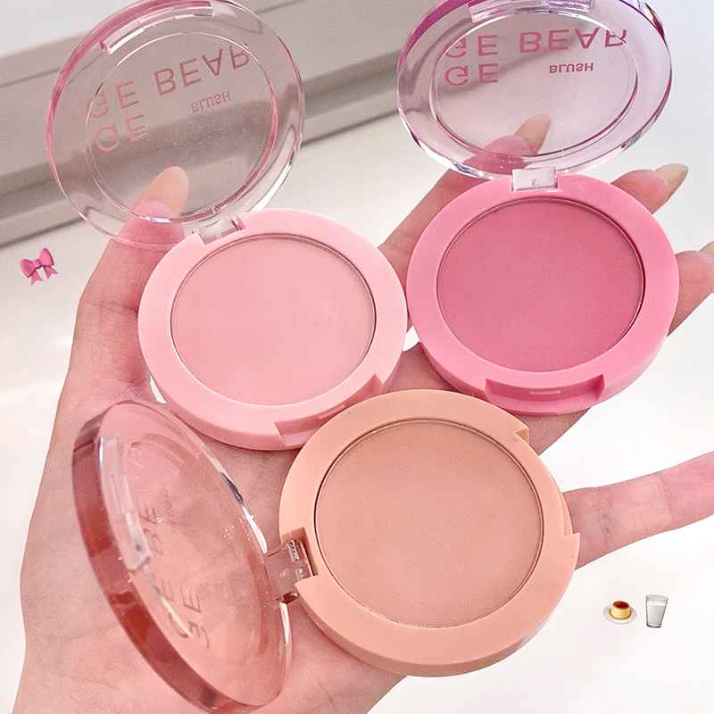 Three pink and beige makeup blush held in a hand with visible brand name.