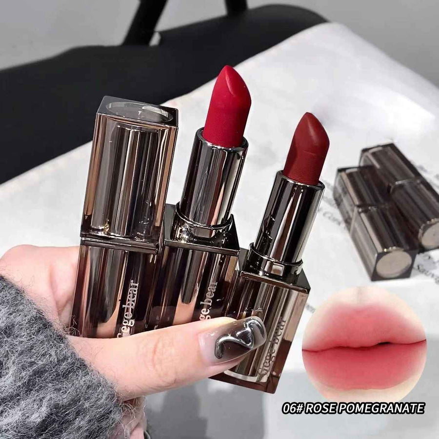Three red lipsticks with brown cases held by a hand, one is open showing the lipstick color.