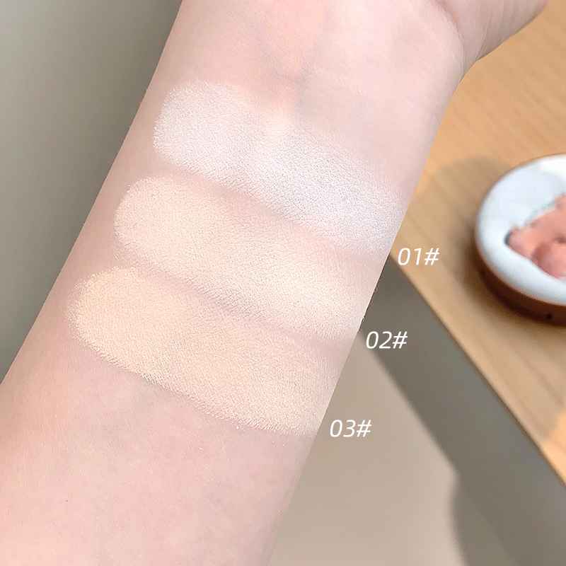 Three swatches of a compact powder  product on a person's arm with labels indicating different shades.