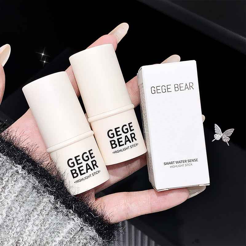 Two 'GEGE BEAR' Blushes  sticks held by a hand with a black background