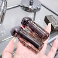 Two gege bear lip glosses held in a hand with a blurred background