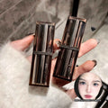 Two makeup products held by a hand with a blurred background