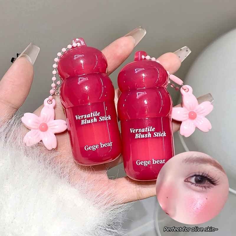 Two red blush sticks with floral designs held by a hand, close-up of blush application on skin.