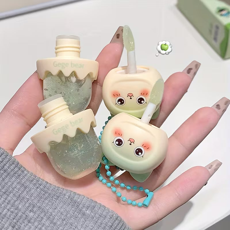 Clear lip oil in a sleek tube shown with a glossy applicator, reflecting a soft, luminous shine. The product appears lightweight and moisturizing, suggesting smooth, hydrated lips with a natural, non-sticky finish.