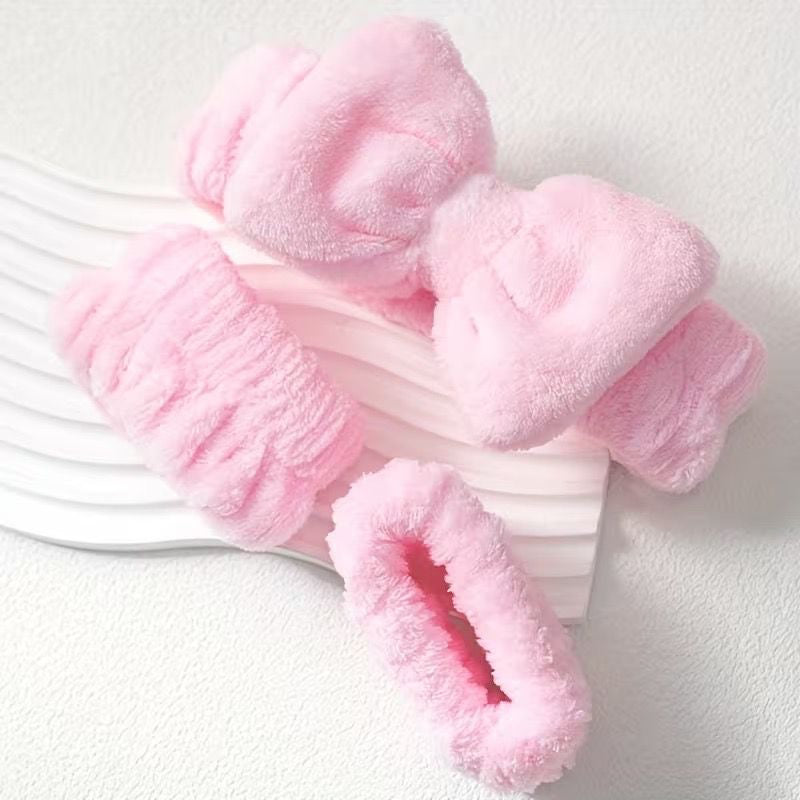 baby pink makeup headbands and wristbands for spa on a tray against the white grainy backgrond 