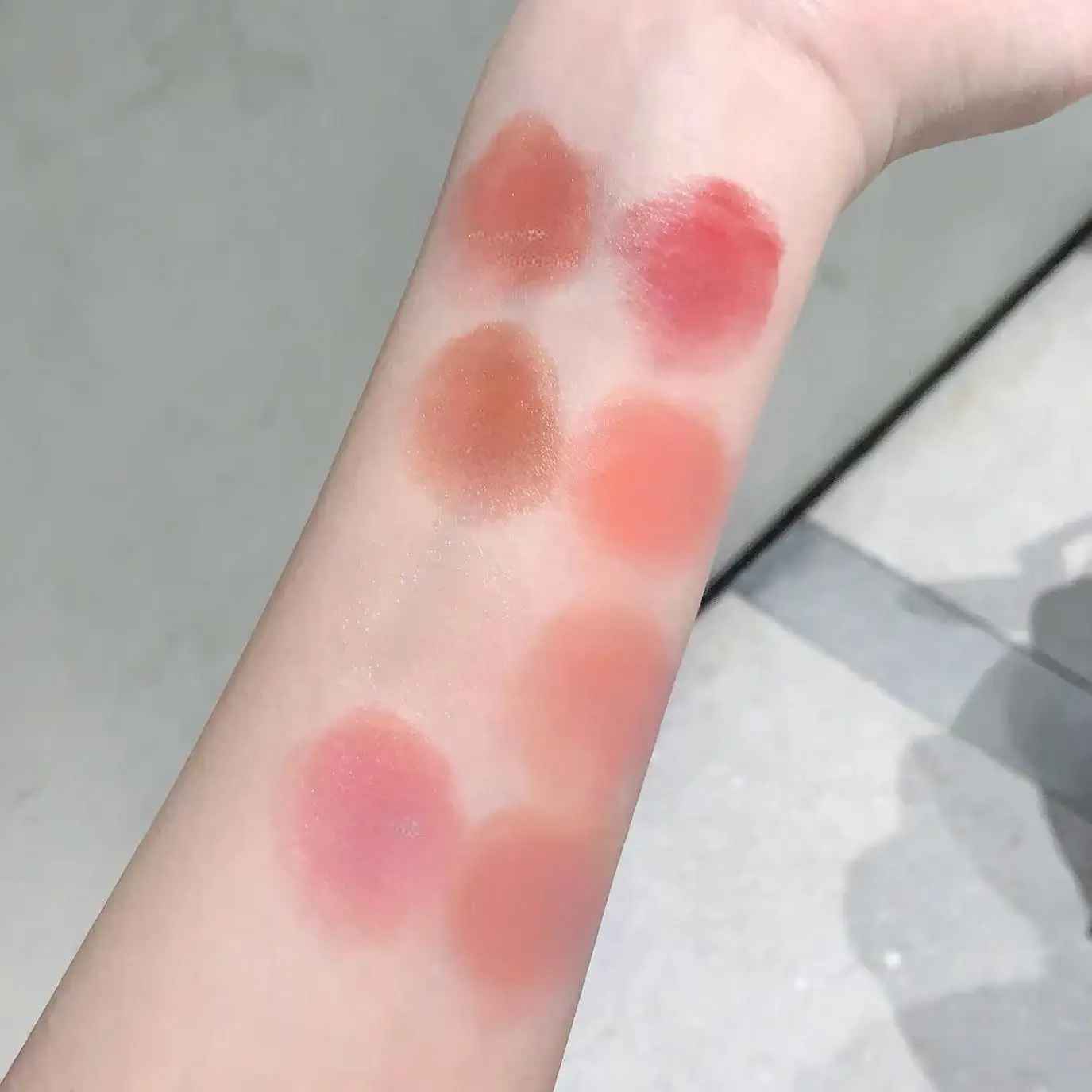 Color swatches of lipsticks on a person's arm with a neutral background