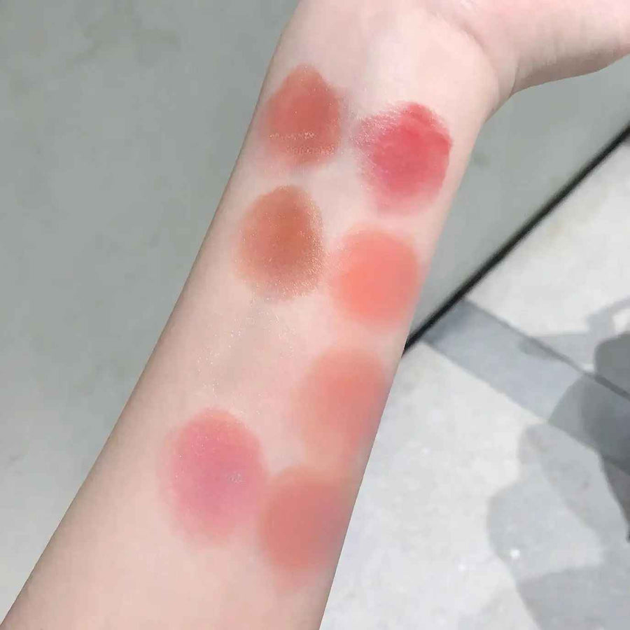 Color swatches of lipsticks on a person's arm with a neutral background