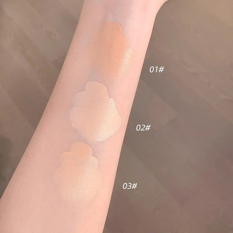Three swatches of concealer online on a person's arm with color codes 01#, 02#, and 03#. The background is blurred.