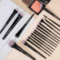 Makeup brushes and a compact powder on a light background