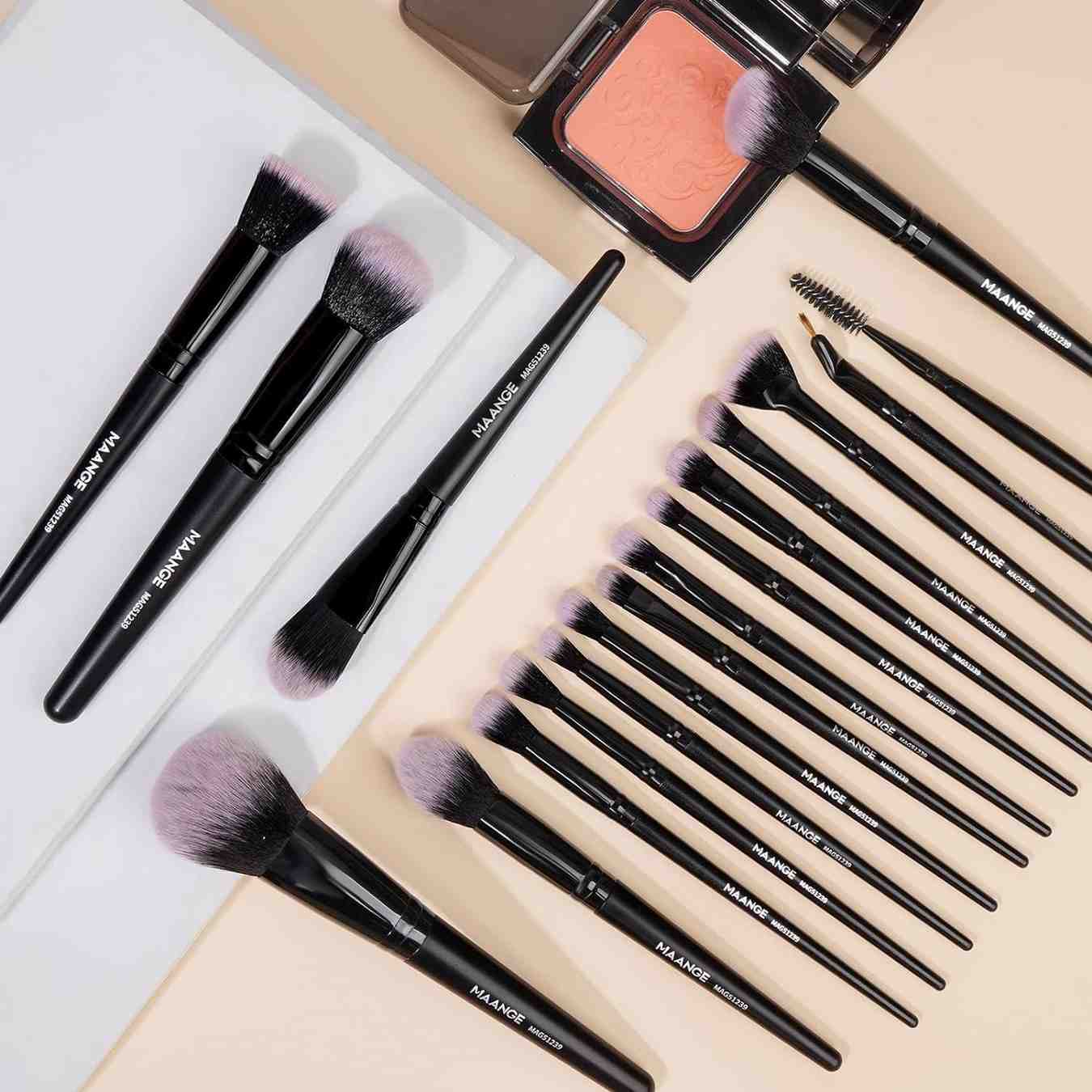 Makeup brushes and a compact powder on a light background