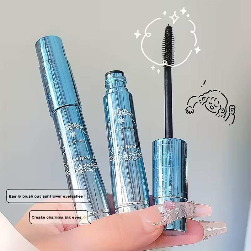 black mascara with open cap, held by a hand against a neutral background in blue japanese packaging 