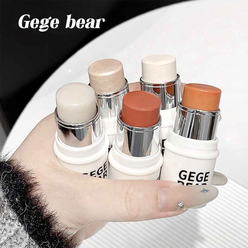 Hand holding  Blushes with  bear bear branding on a white surface.