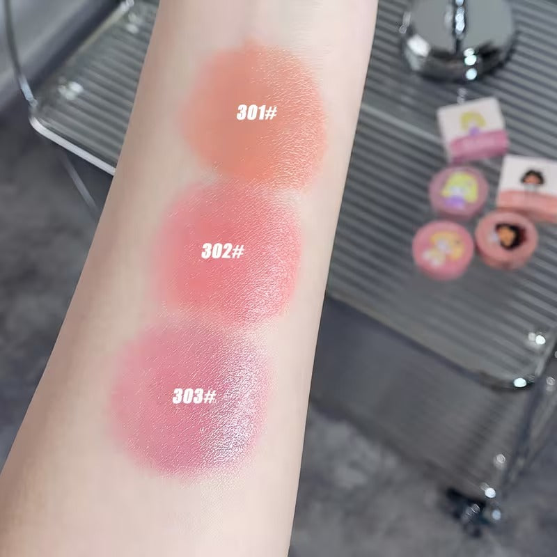 Three swatches of blush on a person's arm with color codes 301#, 302#, and 303#. The background is blurred but appears to be a vanity table.