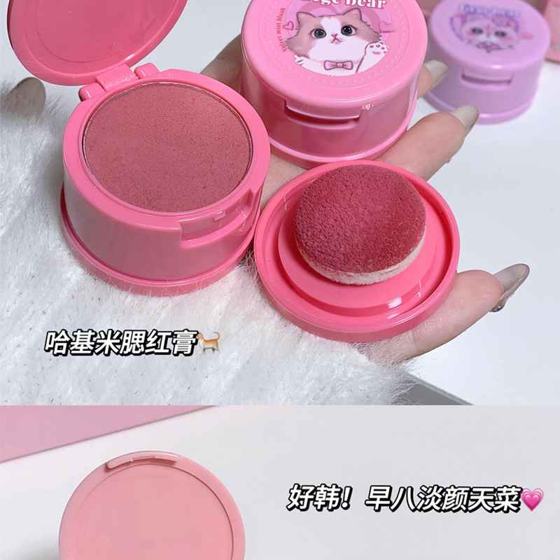 showing pigmentation of a dark brown blush on a puff on a models hand 