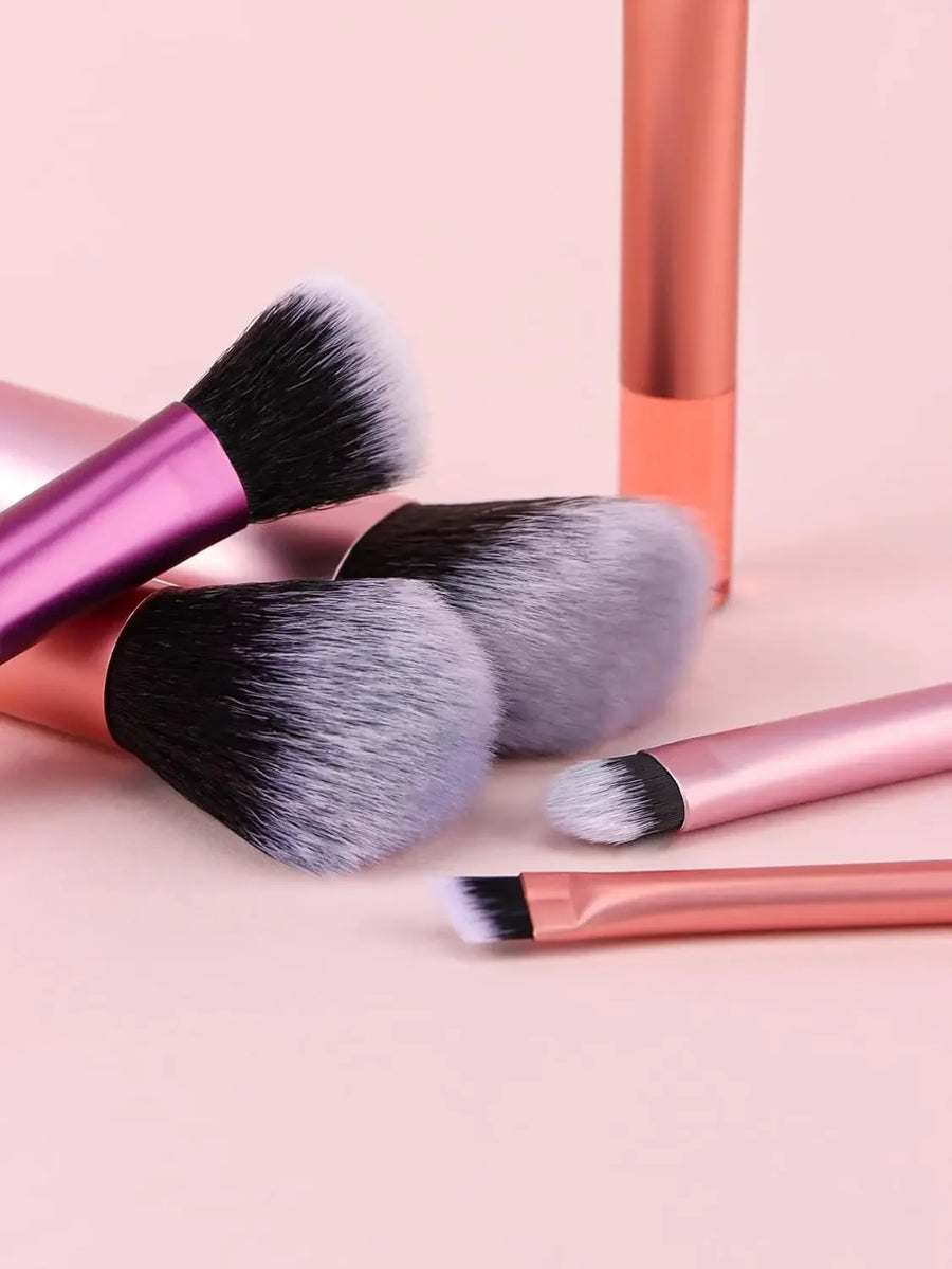 Makeup brushes with pink and rose gold handles on a light pink background