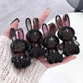 Hand holding six black rabbit-shaped lip gloss  on a light background