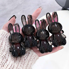 Hand holding six black rabbit-shaped lip gloss  on a light background