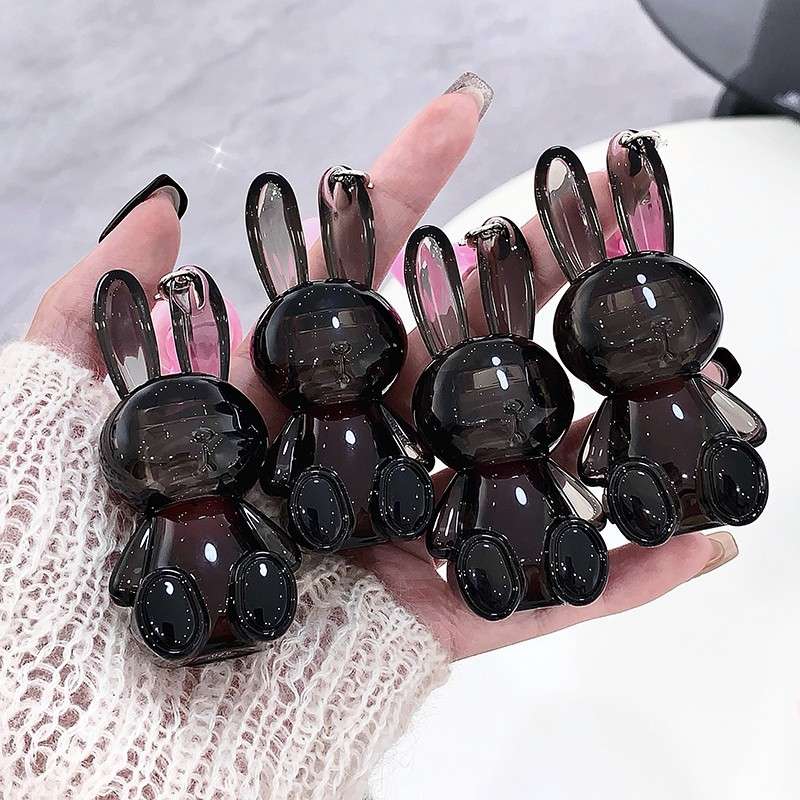Hand holding six black rabbit-shaped lip gloss  on a light background