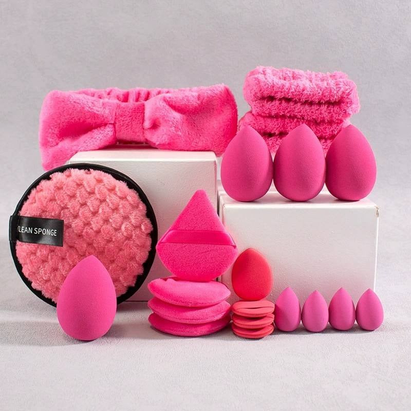 Collection of dark pink beauty tools including sponges, headbands, wristbands and a towel on a gray background