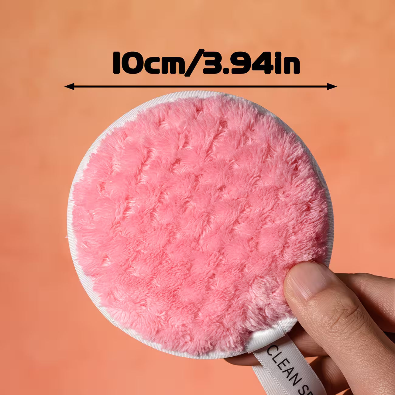 a hand holding pink makeup remover pad showing clear dimension on a bold text on the top 10 cm written 