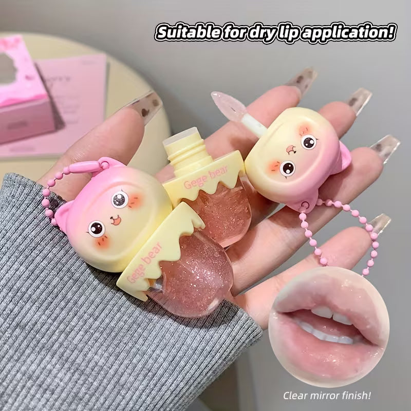 Clear lip oil in a sleek tube shown with a glossy applicator, reflecting a soft, luminous shine. The product appears lightweight and moisturizing, suggesting smooth, hydrated lips with a natural, non-sticky finish.