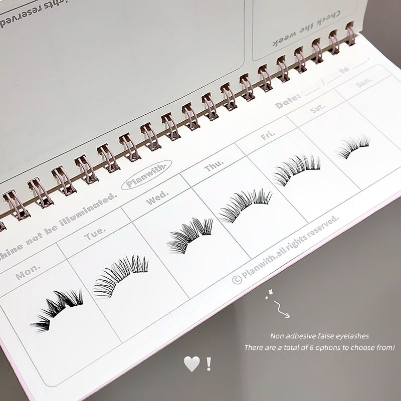 Spiral-bound planner with false eyelashes displayed on each page