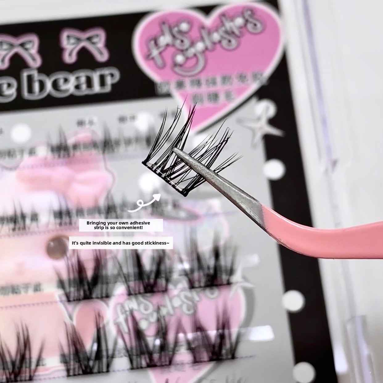 False eyelashes with a pink holder and packaging in the background