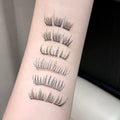 Set of false eyelashes displayed on a person's arm against a neutral background