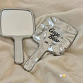 Handheld mirror and paddle with 'Gege Bear' branding on a beige surface