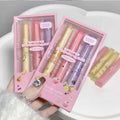 Two pink boxes containing lip lipstick with a hand holding one of them.
