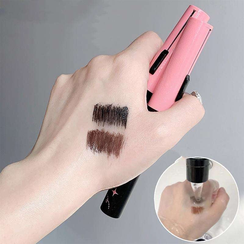 Hand holding a pink and black gege bear mascara with swatches on the palm against a gray background.