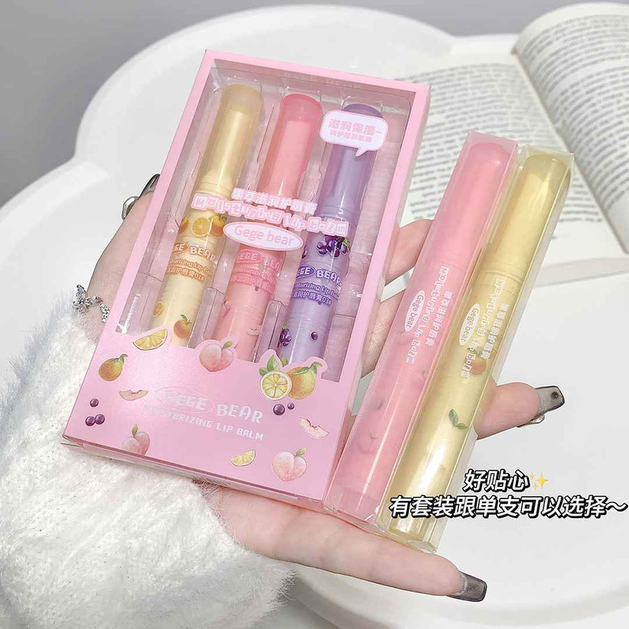 Set of lip balms in a pink packaging held by a person