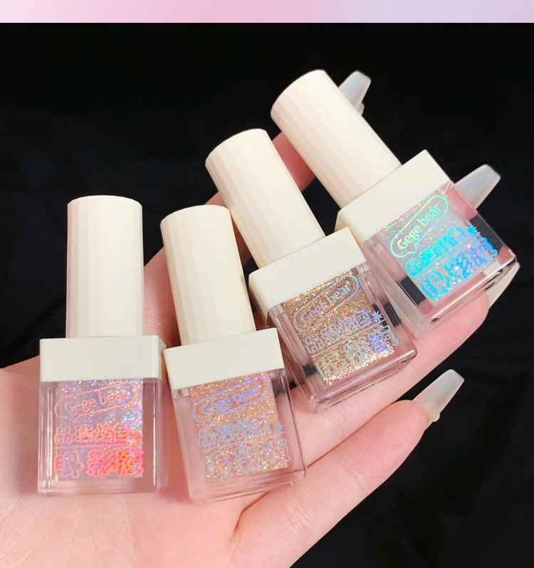 Set of liquid shimmer eyeshadow bottles with glittery contents held in a hand against a dark background