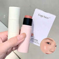 Hand holding makeup highlighter stick with a Gege bear branded box on a gray background