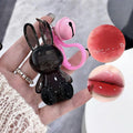 Black rabbit-shaped lip gloss held by a hand with close-up insets of the product.