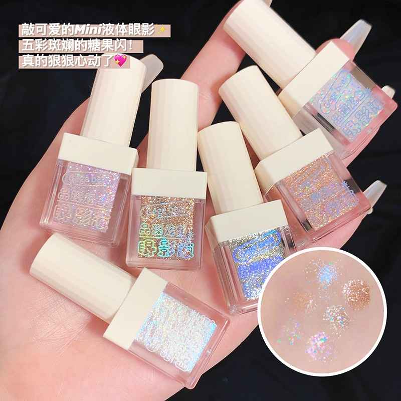 Mini liquid shimmer eyeshadows with glittery contents held in a hand, with close-up of glitter on skin.