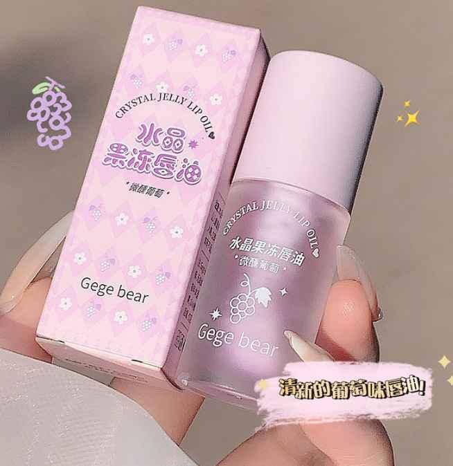 Crystal jelly lip oil with packaging held by a hand on a neutral background grapes flavoured 