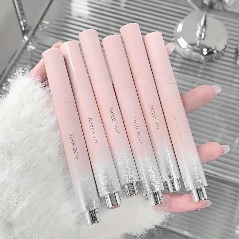 Set of pink gradient lip glosses held by a hand with a blurred background