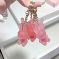 Pink bunny keychain lipstick with gold chains held by a hand against a white background