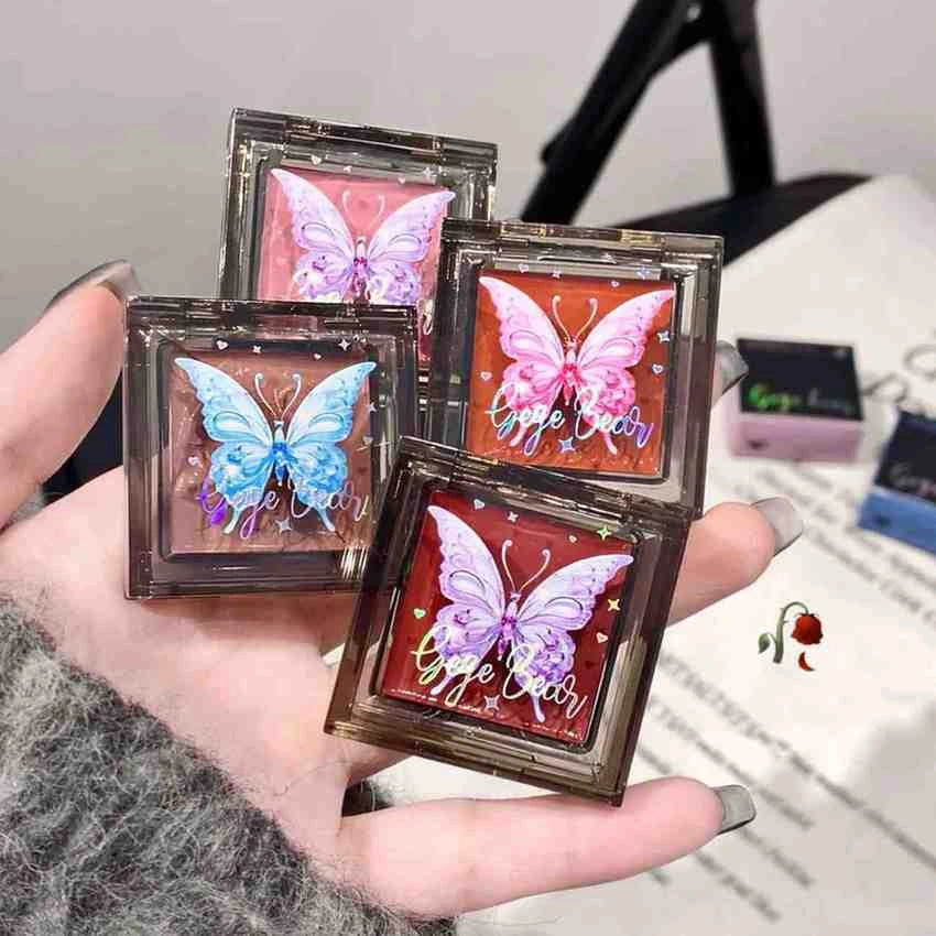 Four butterfly-themed blush held in a hand with a blurred background.