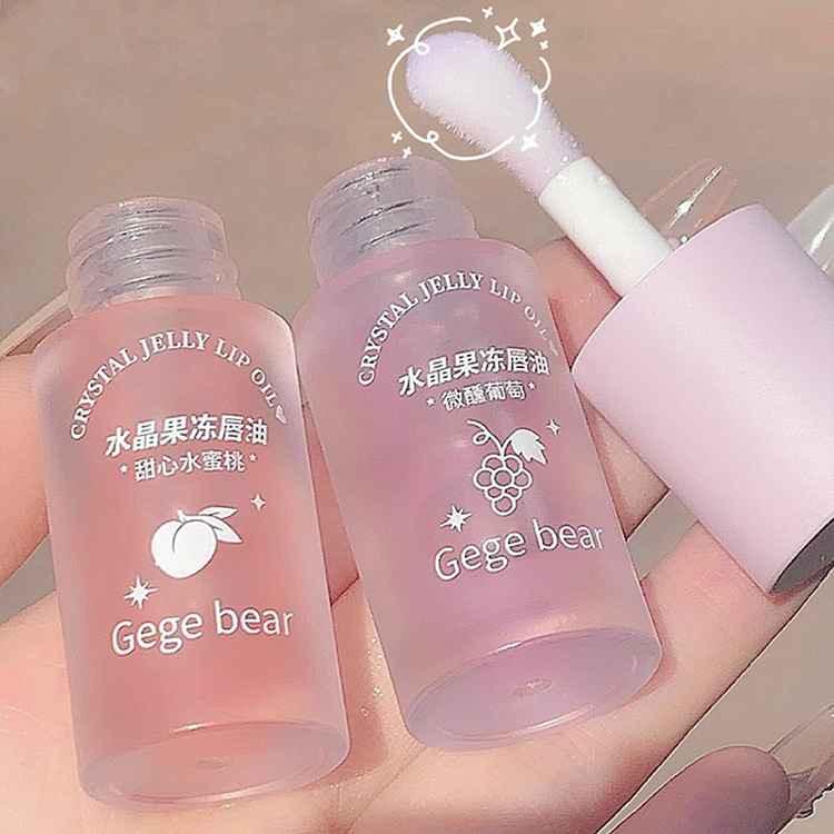 Two pink lip oil bottles with a brush on a neutral background